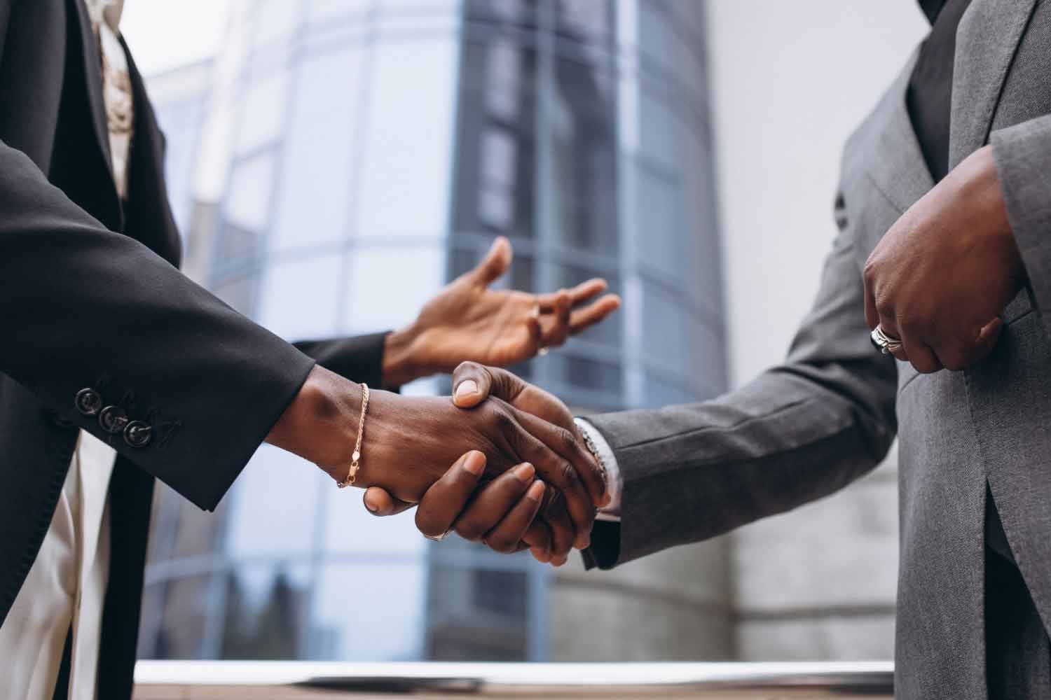 Two persons shaking hands in a corporate setting depicting a business deal