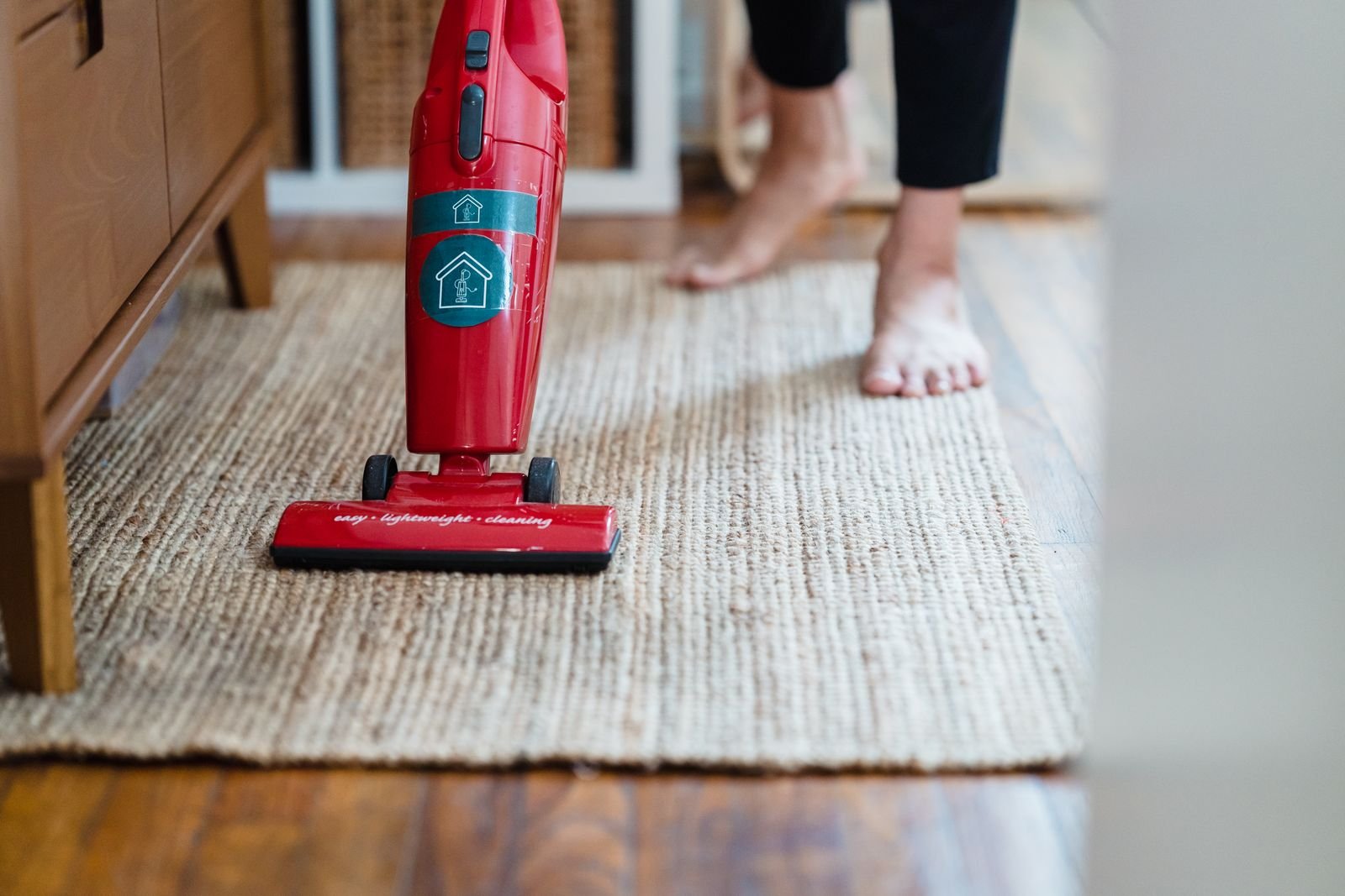 An upright vacuum on a woven rug in a rented home
