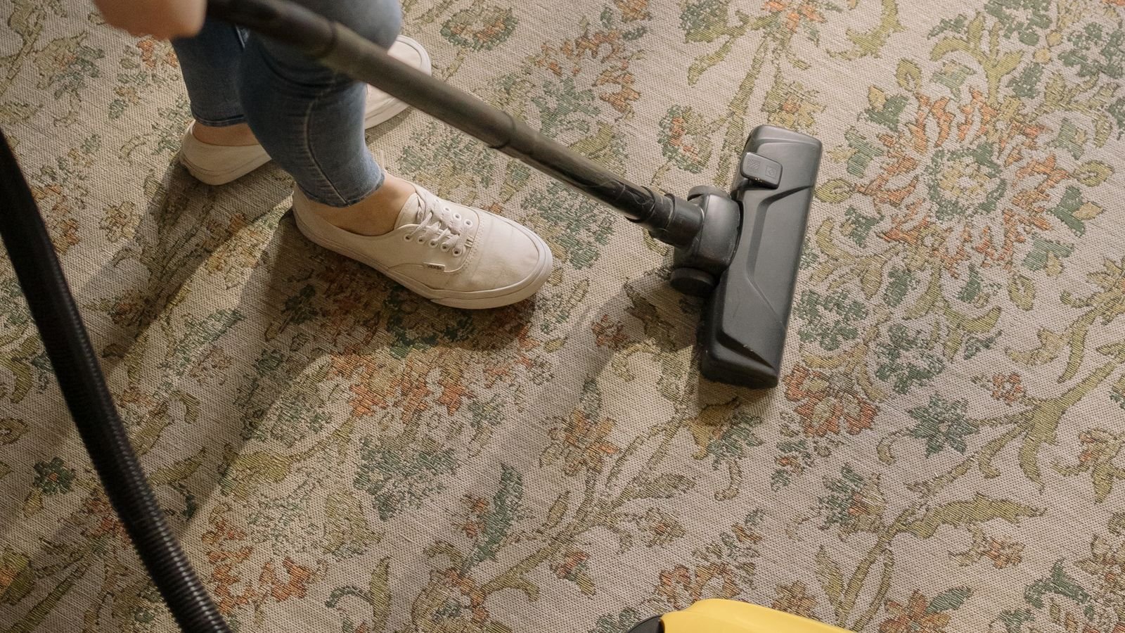 carpet-cleaning-frequency-manchester Person vacuuming a patterned carpet in a home