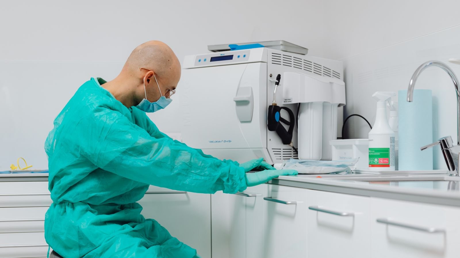 clinic-cleaning-manchester Cleaner in scrubs disinfecting a clinical worktop in a treatment room