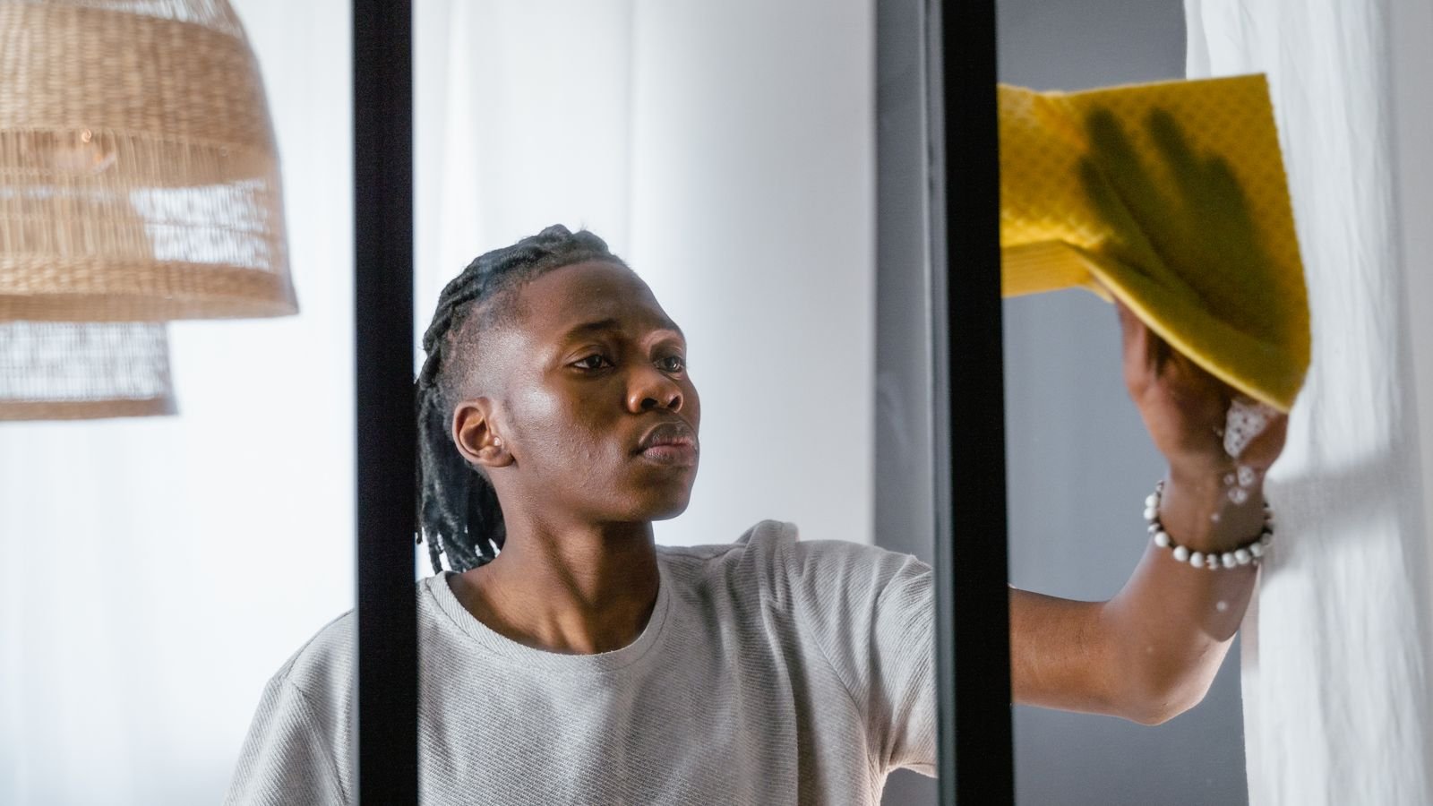 Man wiping condensation from a window with a yellow cloth