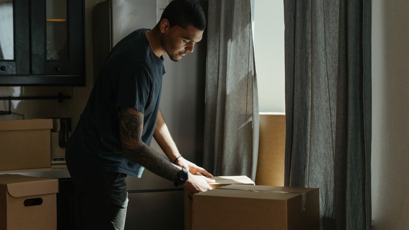 Man unpacking a moving box in a new kitchen