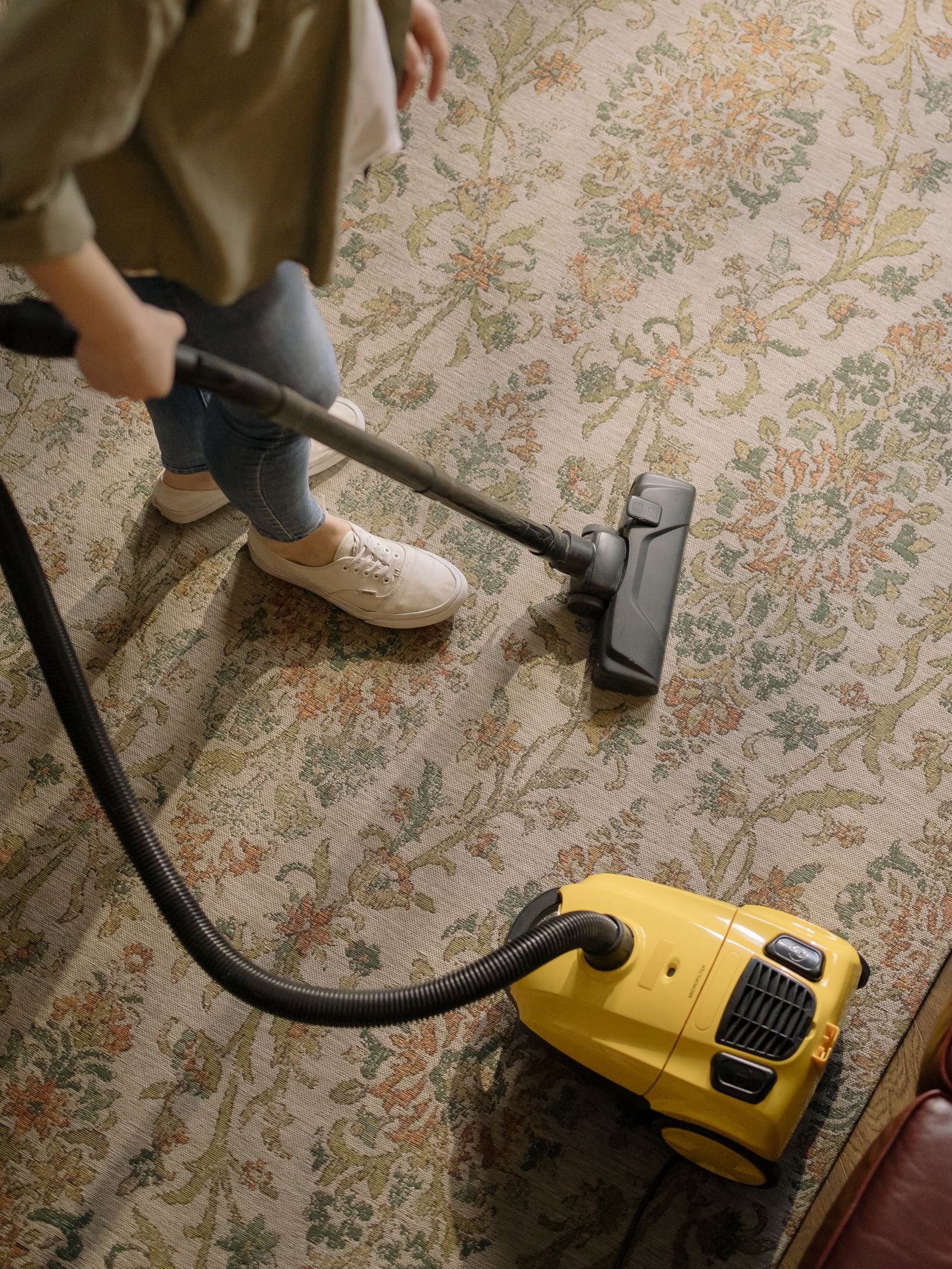 An overhead view of a canister vacuum cleaning a patterned carpet