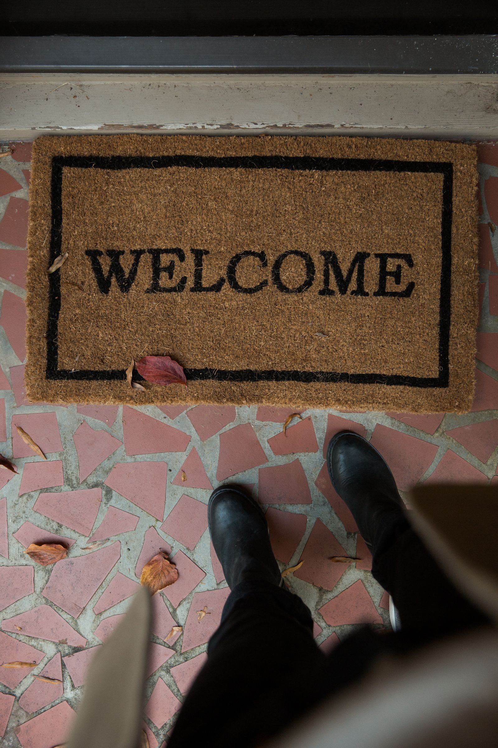Boots stopped at a coir welcome mat inside a front door