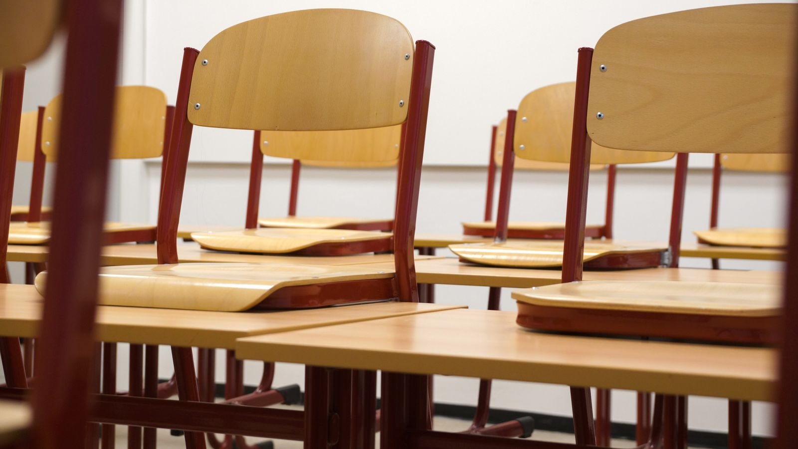 Empty classroom with chairs stacked on desks ready for cleaning