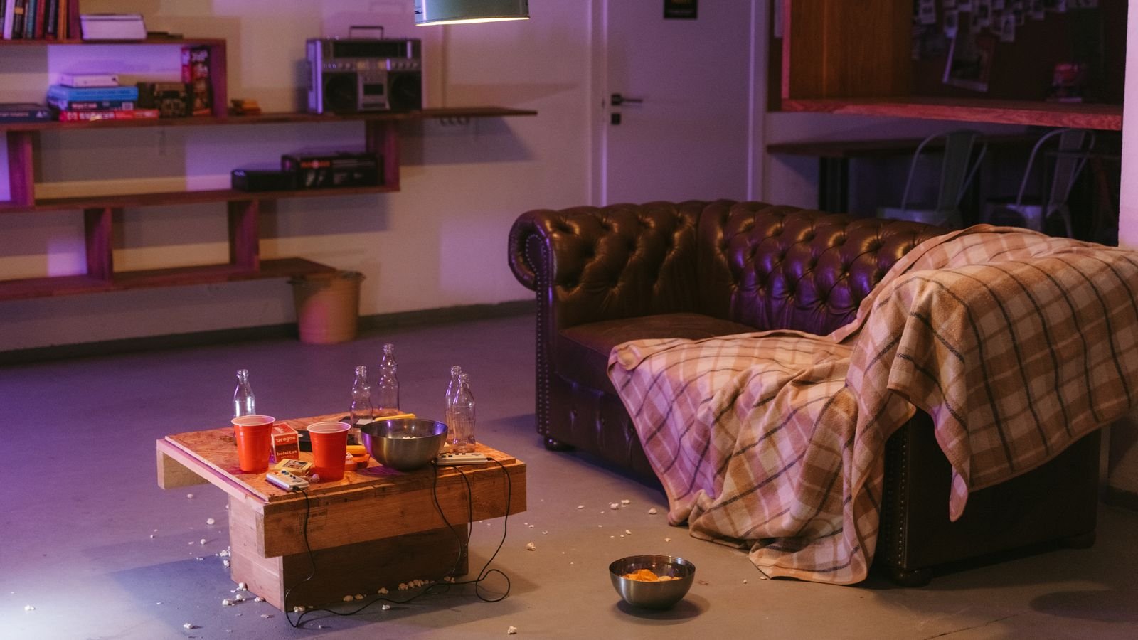 Living room after a party with snacks scattered on the floor and bottles on the coffee table