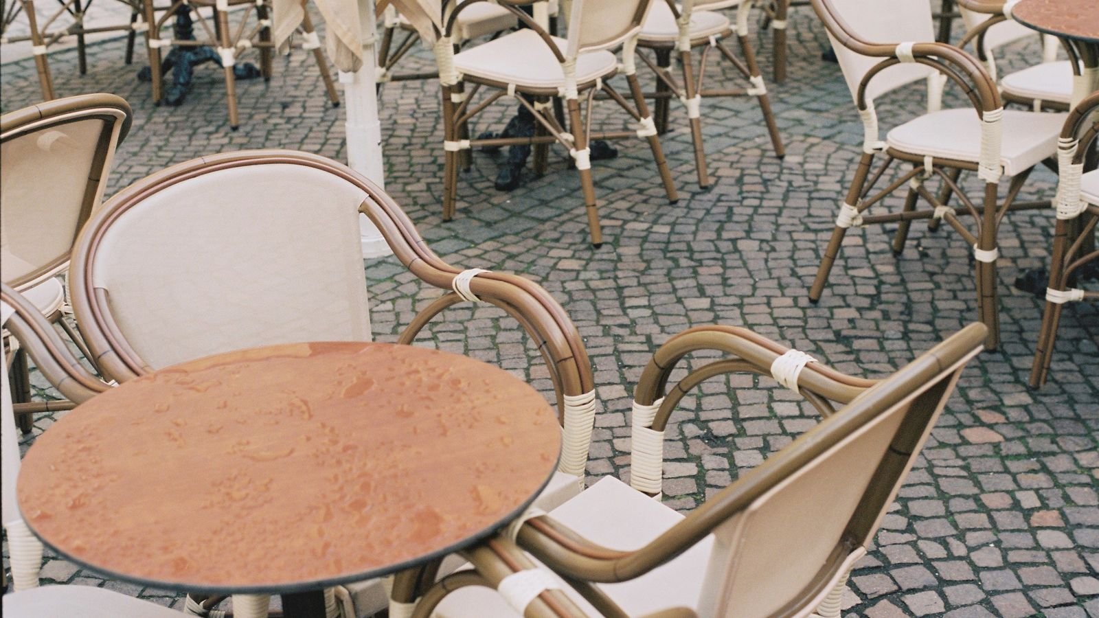Empty outdoor cafe chairs and round tables on a paved terrace. Empty outdoor cafe chairs and round tables on a paved terrace.