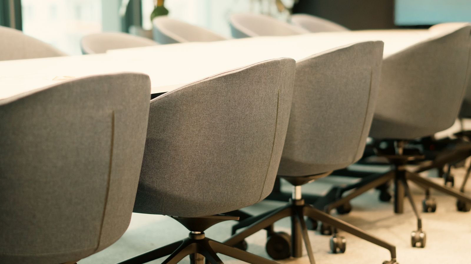 Grey upholstered meeting chairs arranged beside a white conference table.