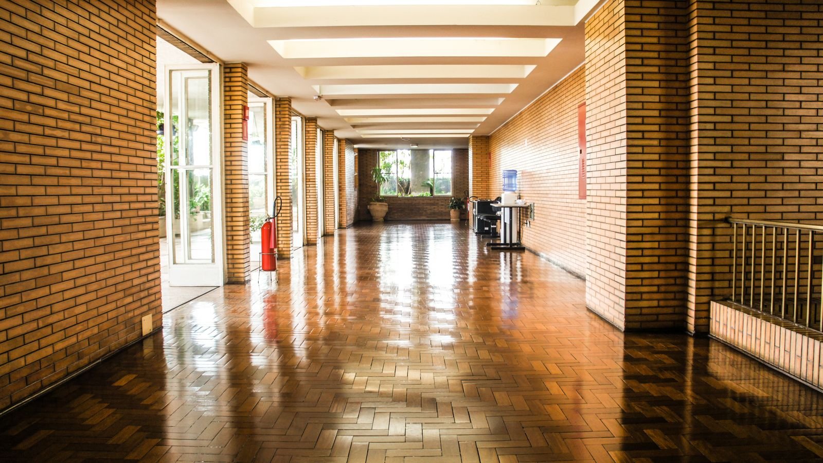 Empty brick-lined school corridor with a freshly polished parquet floor and no pupils in sight