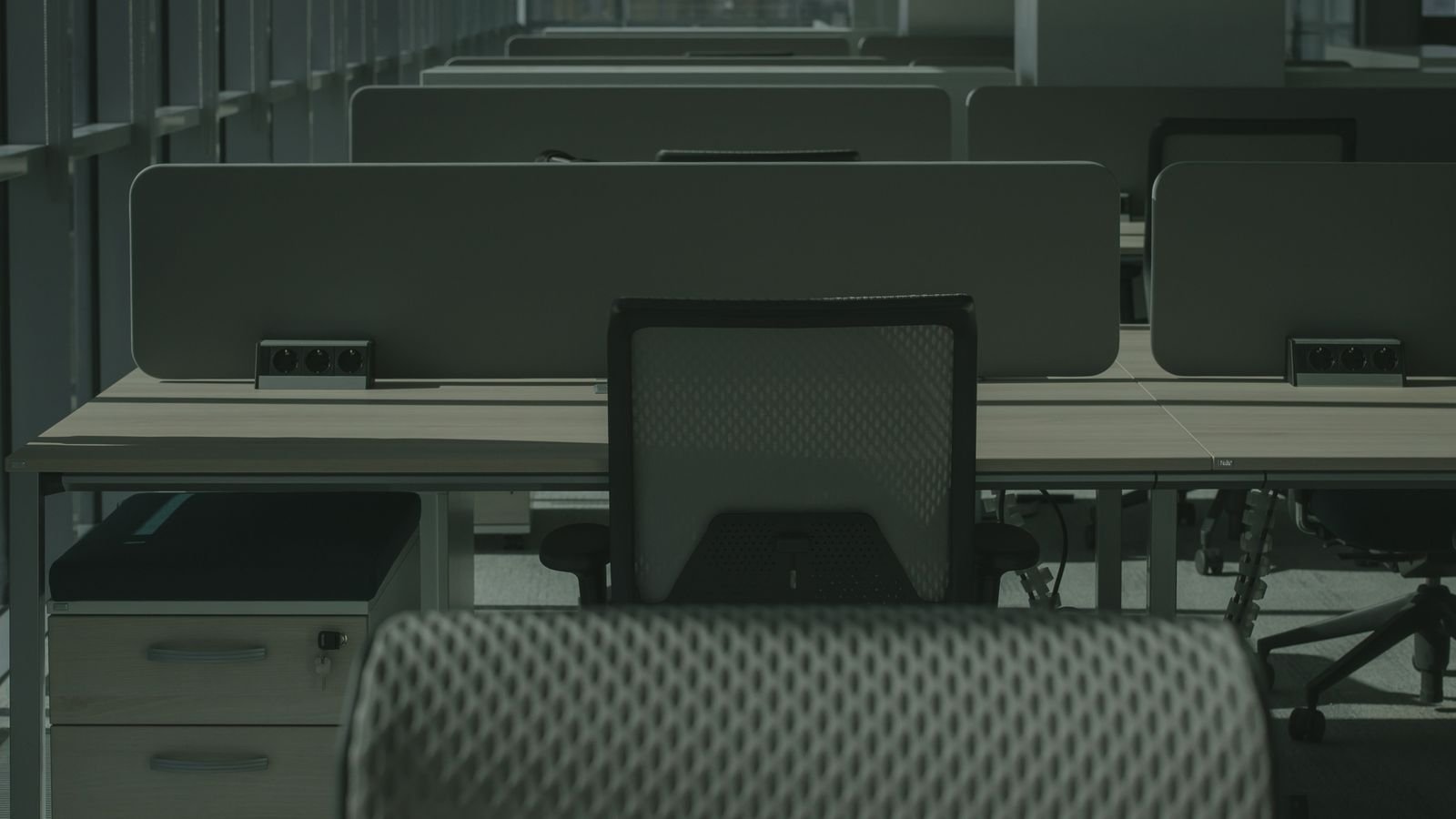 Empty open plan office with desks, divider screens and mesh chairs after hours