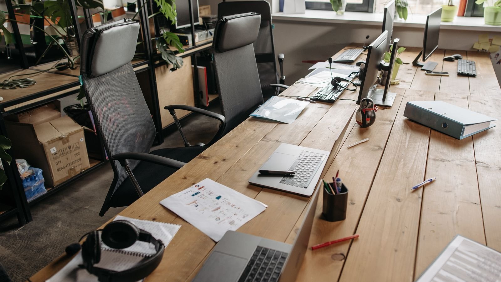 Shared office desks with laptops and paperwork left on the surfaces Shared office desks with laptops and paperwork left on the surfaces