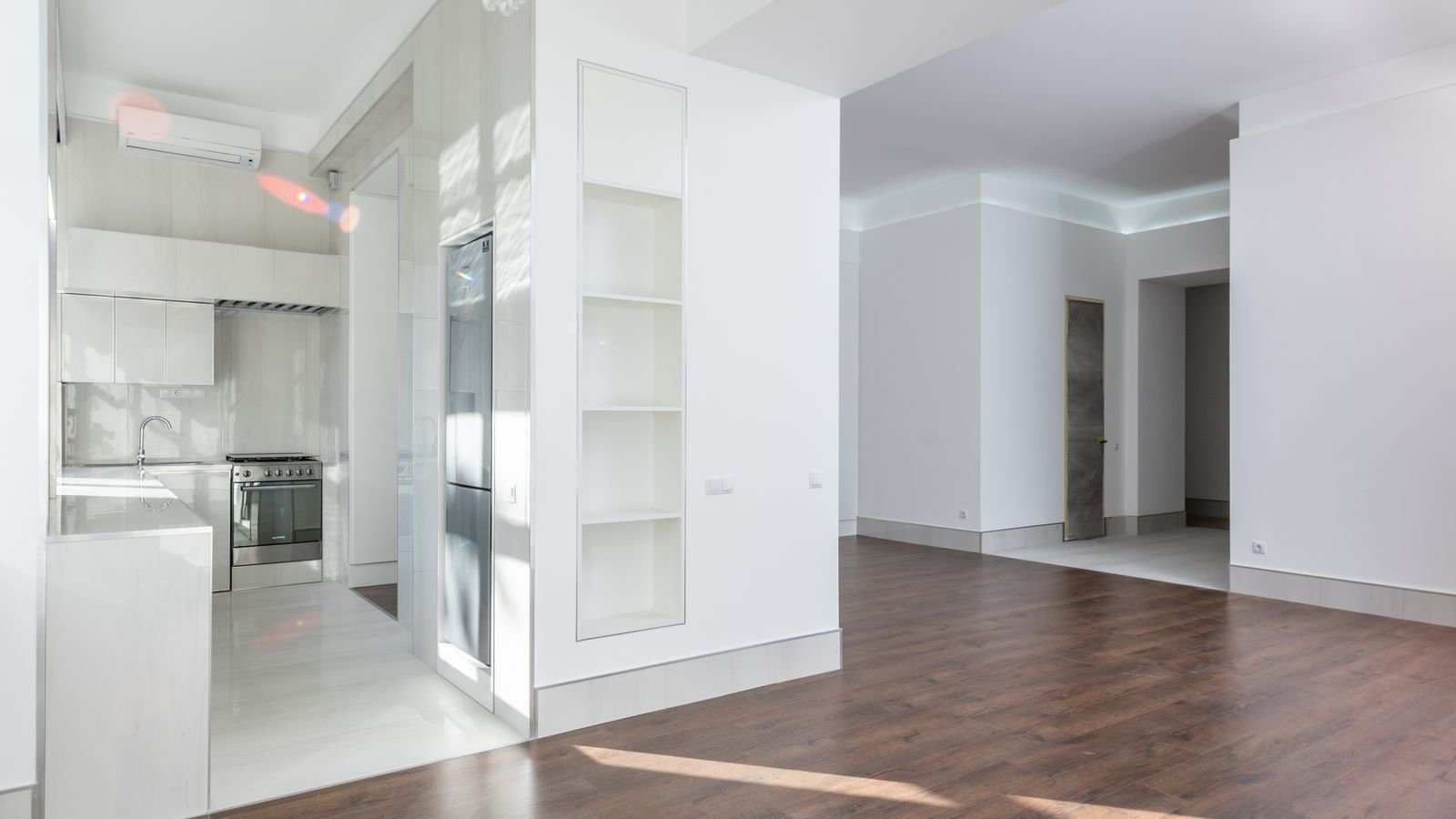 Bright empty apartment with a white kitchen and wooden floor, ready for the next guest.